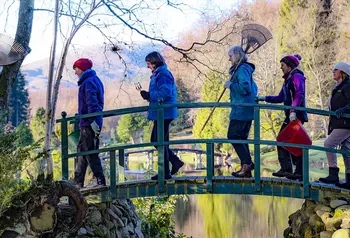 People walking across a bridge with gardening equipment in their hands