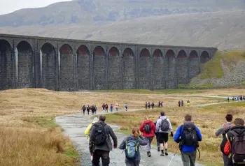 People walking along a country path by a viaduct in Yorkshire