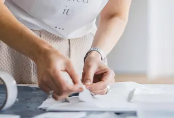 A person's hands handling a folded piece of white linen on a flat surface