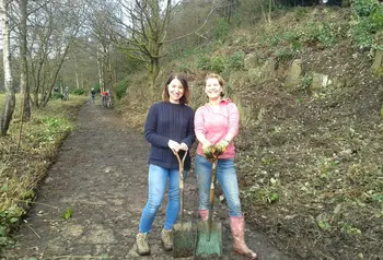 Two volunteers using shovels to help clear a footpath