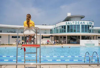 Saltdean Lido with a lifeguard sitting in front observing the outdoor pool