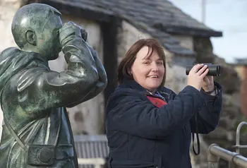 Woman with binoculars next to statue