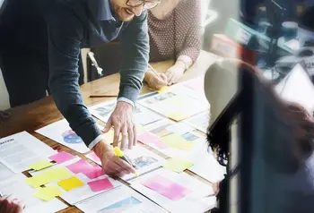 People working on an office desk with bright sticky notes