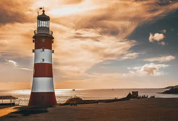 A red and white lighthouse at sunset