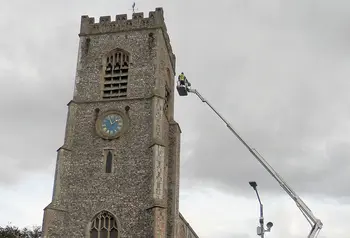 The tower of St Nicholas with a person on a crane assessing the tower roof