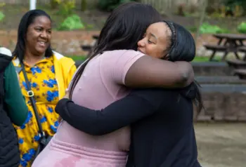 Photograph of two women hugging each other in a park