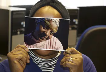 A woman holds a photograph over her face