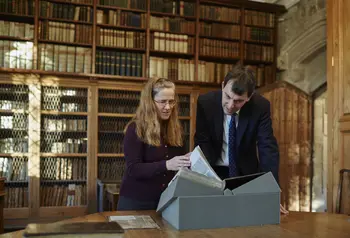 Cathedral Archivist Emily Naish and John Glen MP examine a book from the collection