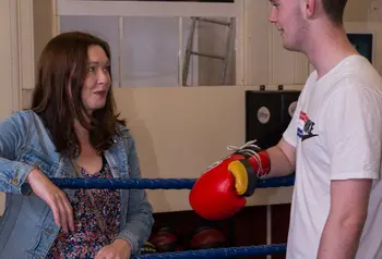 A woman talks to a young male boxer