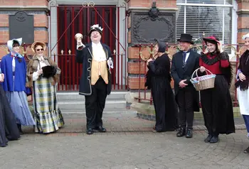 A bell ringer and other people in historic dress