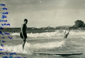 A black and white photograph of a surfer on a long board