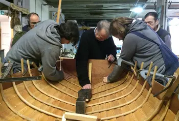 People working on the inner side of the hull of a wooden boat