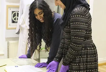 Hanna Ahmed (left) and Nazish Majid looking at items from the archive at The Peace Museum, Bradford