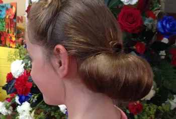 A young lady with a 1940s style chiffon beside a church flower display