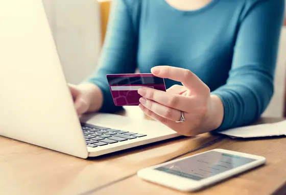 Person using laptop whilst holding bank card