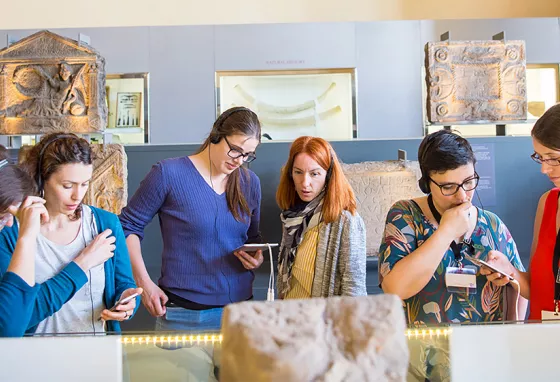 Six people using devices at a museum exhibition 