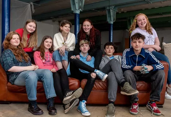 Young people gathered around a red sofa