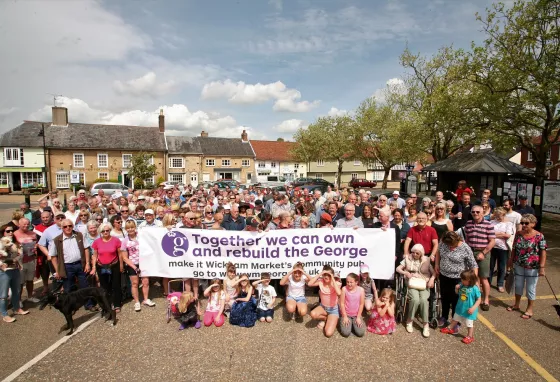 Wickham Market community holding up a banner to save The George pub.