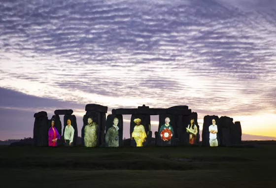 Stonehenge at sunset illuminated with eight people