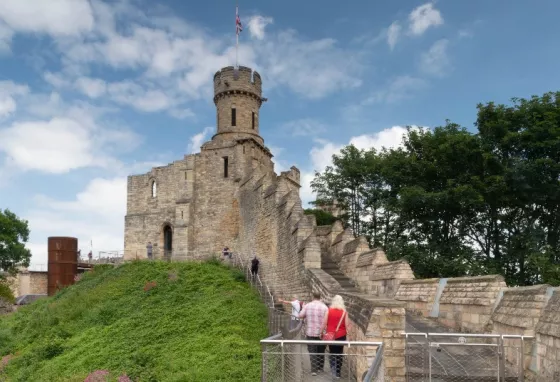 People walking up steps to a castle with turret