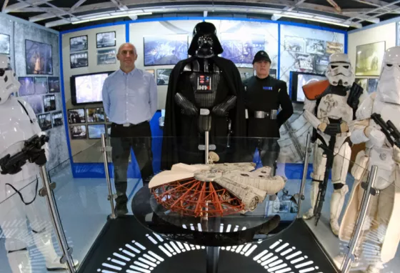 Storm Troopers and Darth Vader standing around a model of the Millennium Falcon