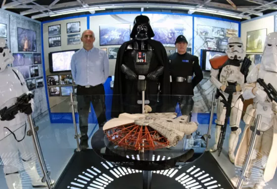 Storm Troopers and Darth Vader surround a model of the Millennium Falcon