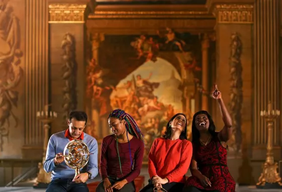 People sitting on a bench in a museum, pointing and looking at an exhibition