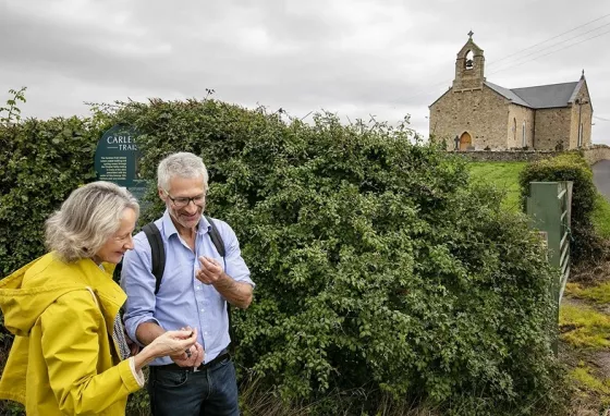 Two people standing with a church on a hill in the background