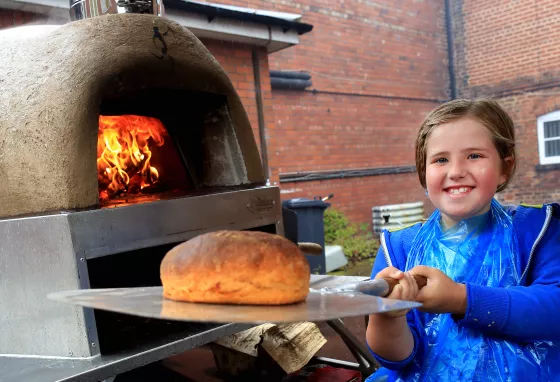 Girl puts loaf in oven