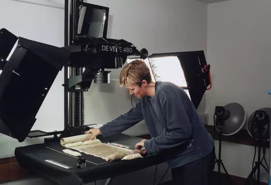 A woman placing a manuscript under a professional digitisation device