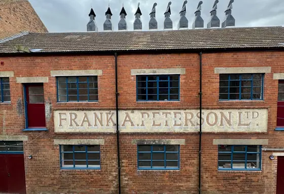 A front of a red brick building with many chimneys on top of the fish smokehouse 