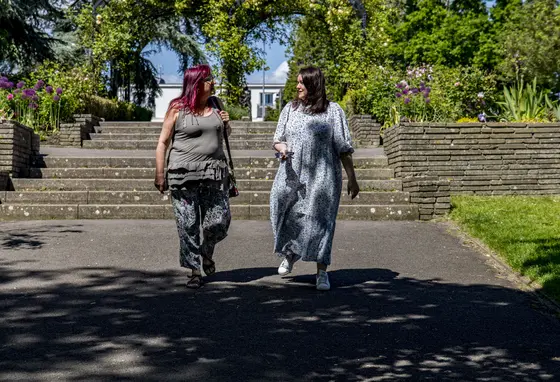 Two people talking and walking through a parkland