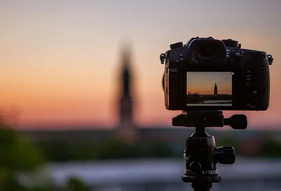 A close-up of a camera showing the digital preview screen, and in the distance, the landmark that's being photographed