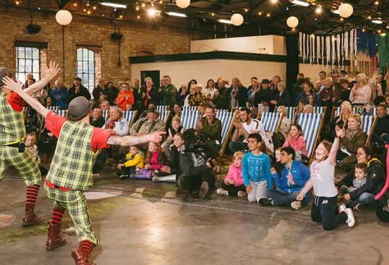 Two clowns performing in front of a crowd seated in deck chairs. Photograph by Graeme Oxby.