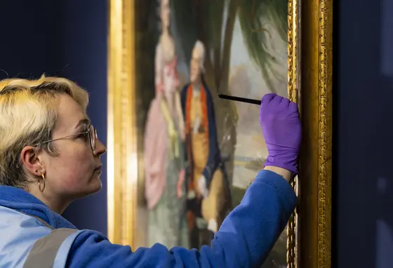 A close up of a person conserving a painting on display in the National Portrait Gallery