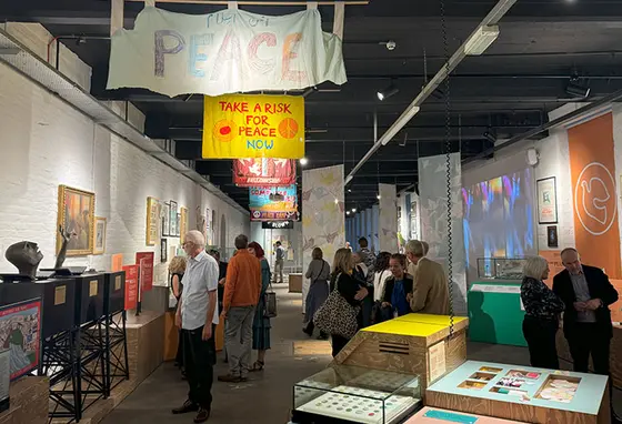 People walk around the exhibits including peace banners and posters