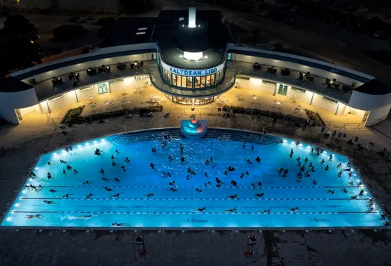 An aerial view of people swimming in the Lido lit up at night