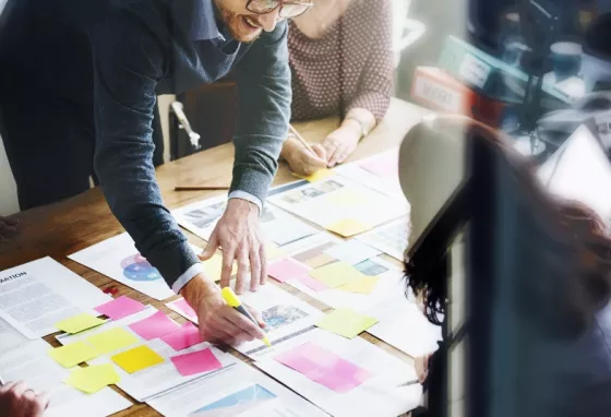 People working on an office desk with bright sticky notes