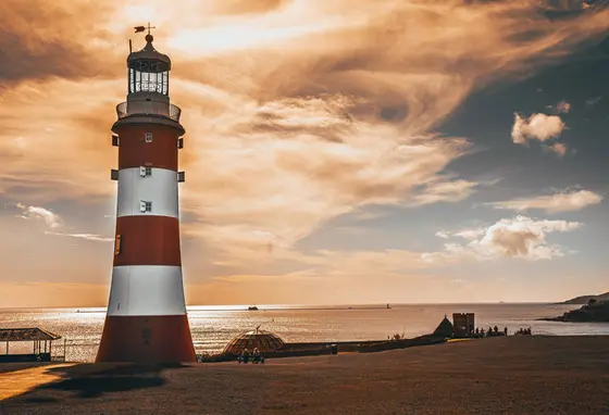 A red and white lighthouse at sunset