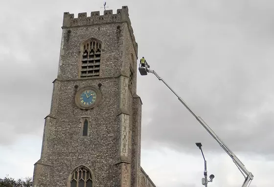 The tower of St Nicholas with a person on a crane assessing the tower roof