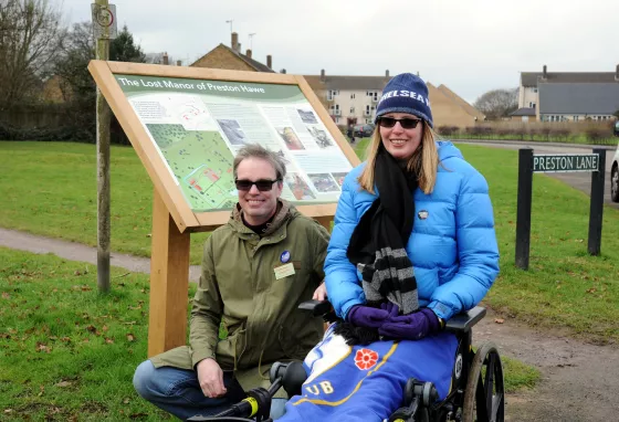 Volunteers Wayne and Antoinette by an information board