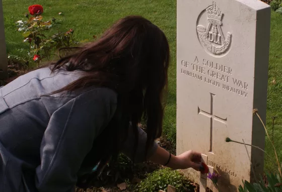 A student from King James I Academy lays a poppy on the grave of an unknown Durham solider