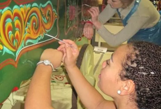 A person painting a colourful design on a wagon