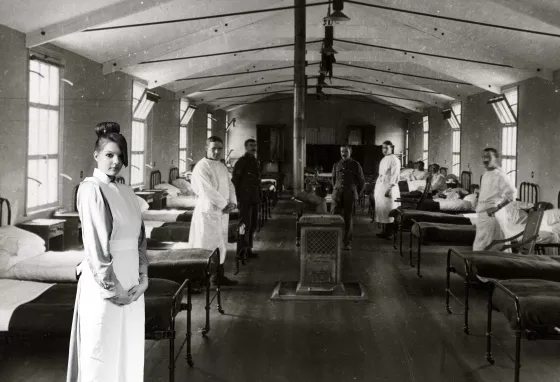 Participant as a VAD (Voluntary Aid Detachment) nurse in front of a green screen with an image of a First World War hospital