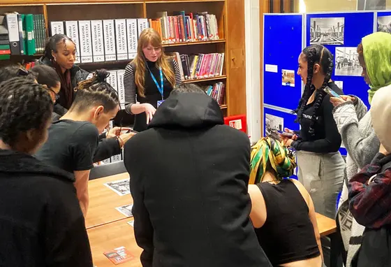 A group of people working around a table looking at research materials