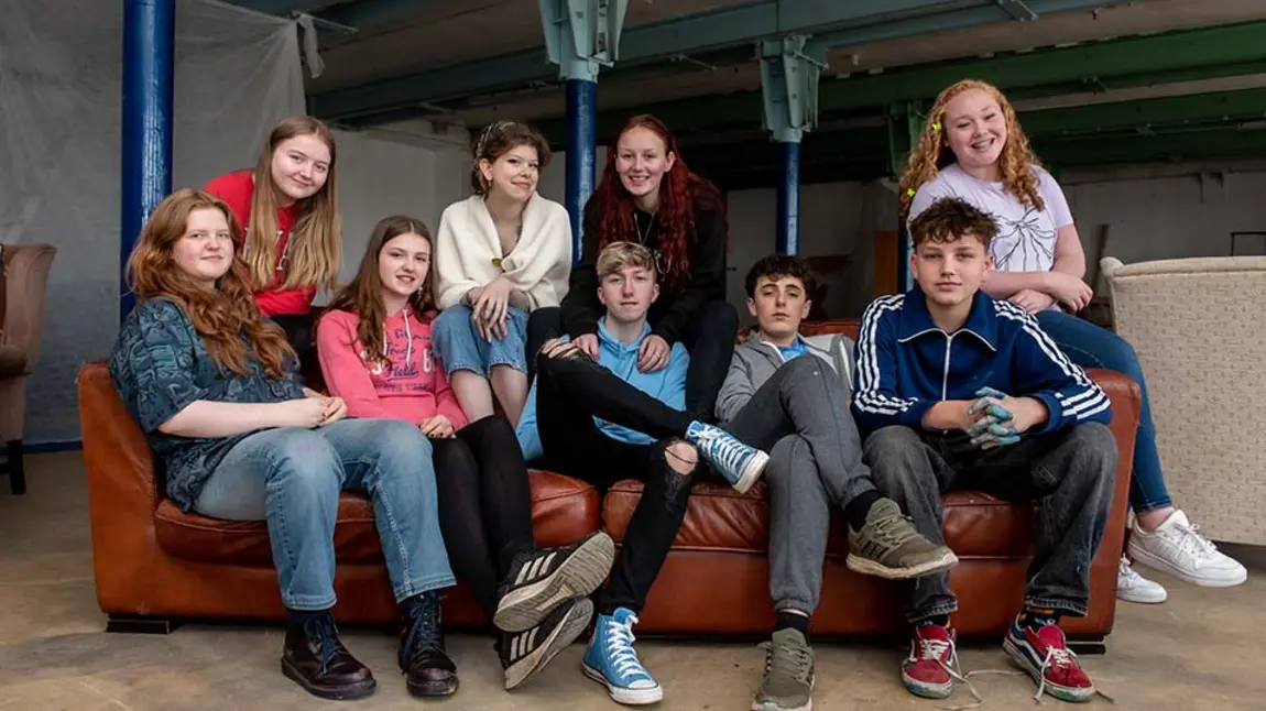 Young people gathered around a red sofa