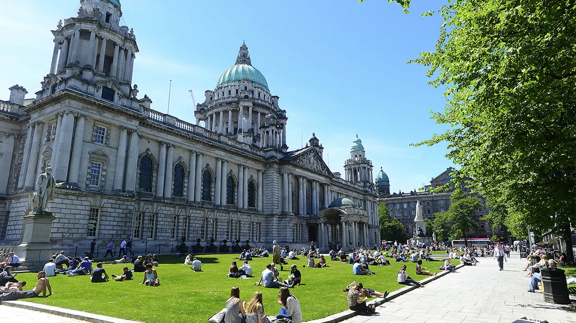 People sitting on grass in front of large building