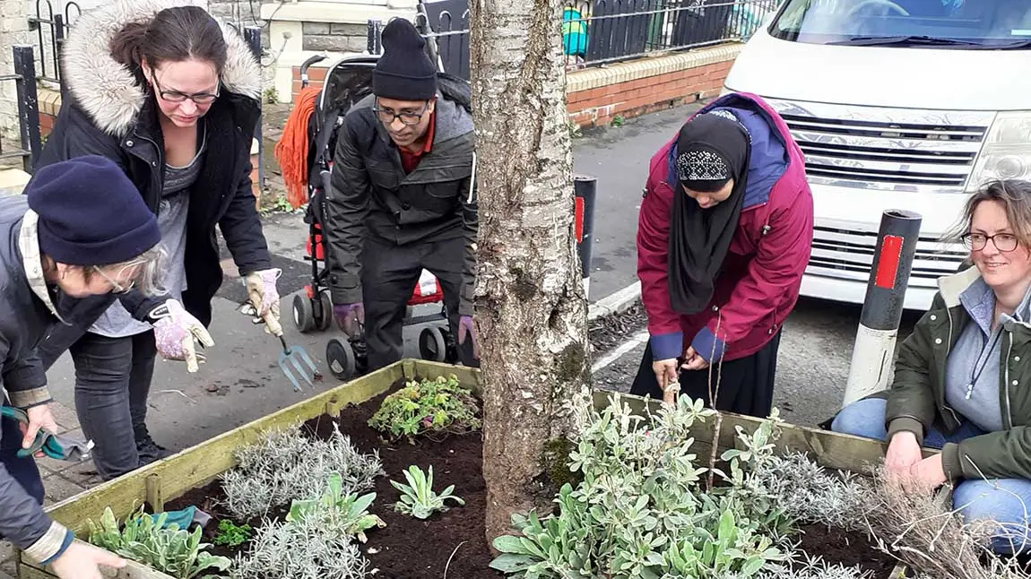 Volunteers tend to a planter in a residential area