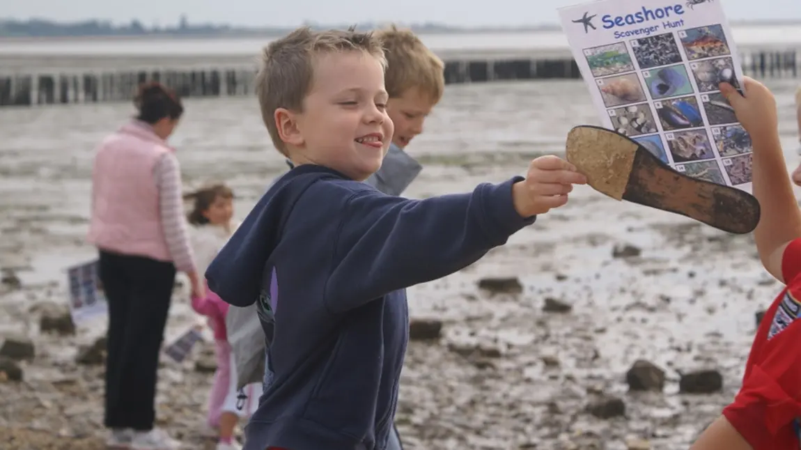 Child playing on a beach with families attending a beach scavenger hunt