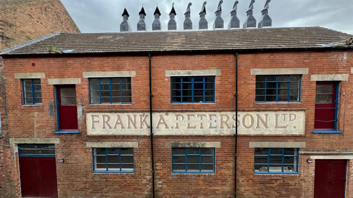 A front of a red brick building with many chimneys on top of the fish smokehouse 